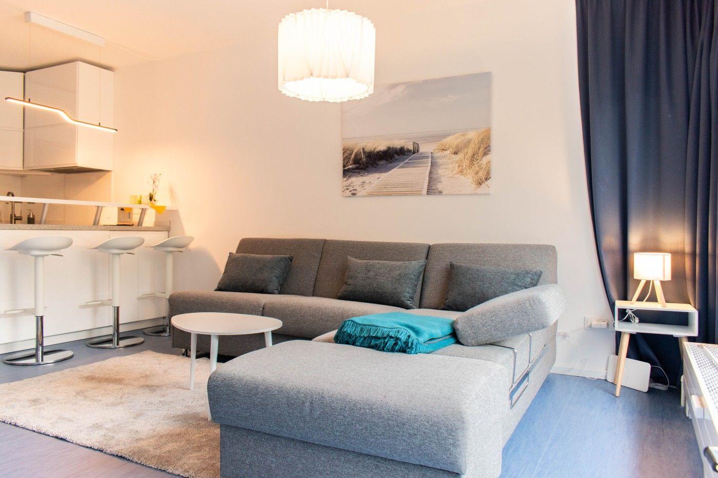 Wohnbereich mit Sofa, Couchtisch und Küchenbereich mit Barhockern.