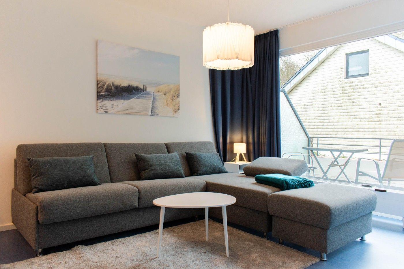 Ein Wohnzimmer mit grauem Sofa, weißem Tisch und Wandbild.