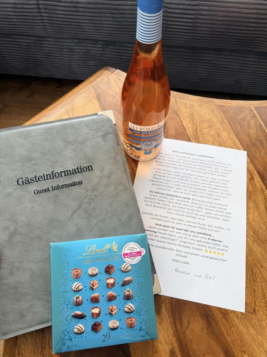 Gästebegrüßung mit Wein, Schokolade und Informationsbroschüre auf Holztisch