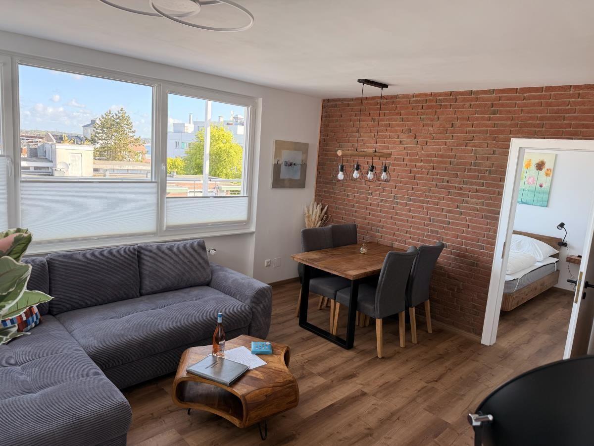 Wohnzimmer mit Sofa, Esstisch und Blick auf die Stadt.