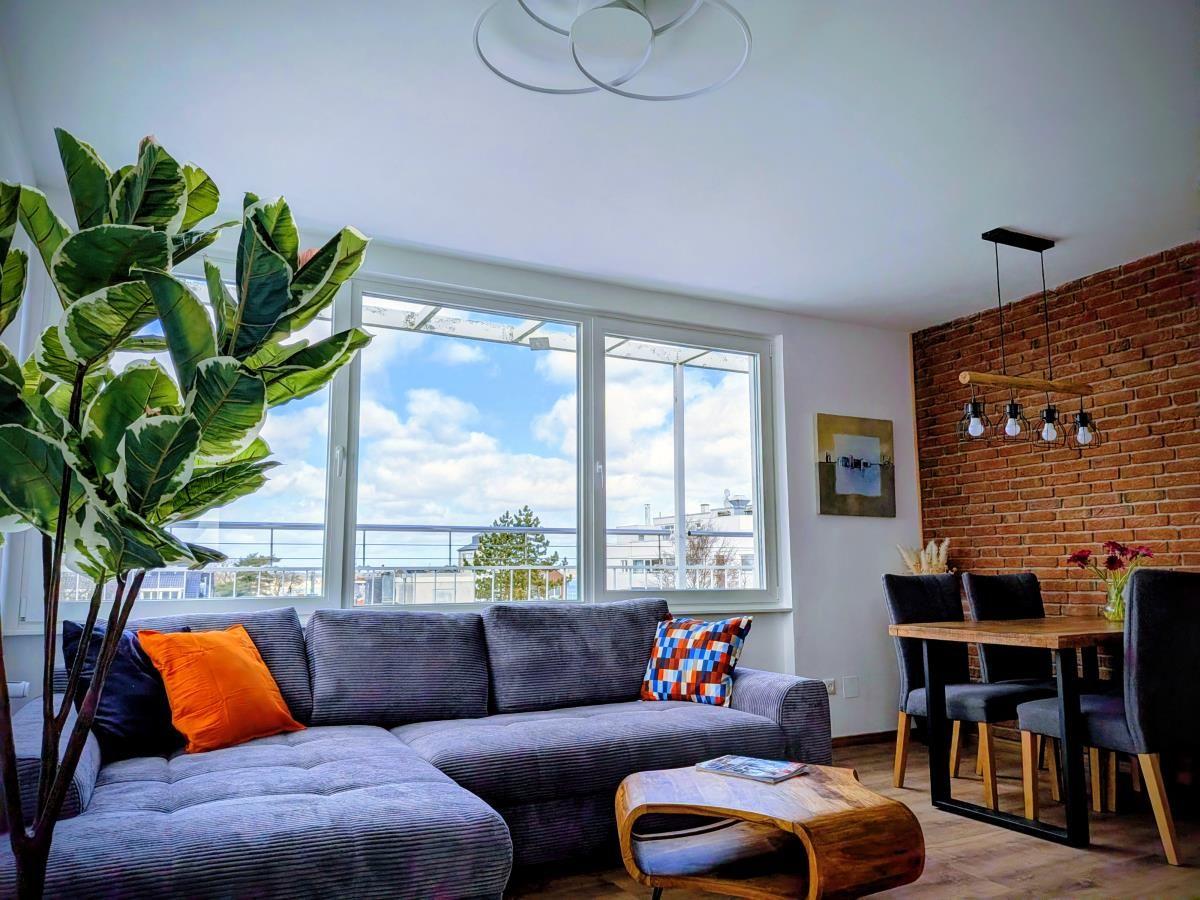 Wohn- und Essbereich mit Sofa, Tisch und Fenster mit Blick.