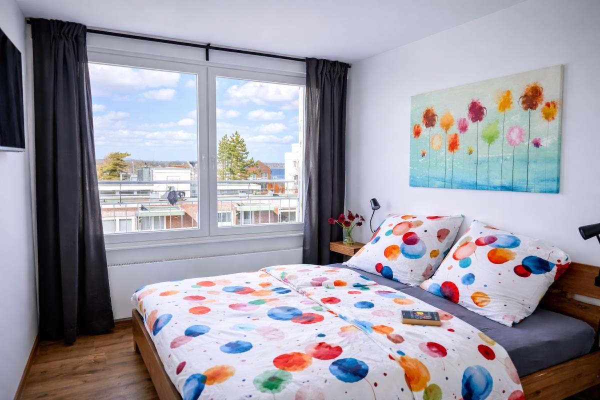 Schlafzimmer mit Bett, Fenster und Wandbild.