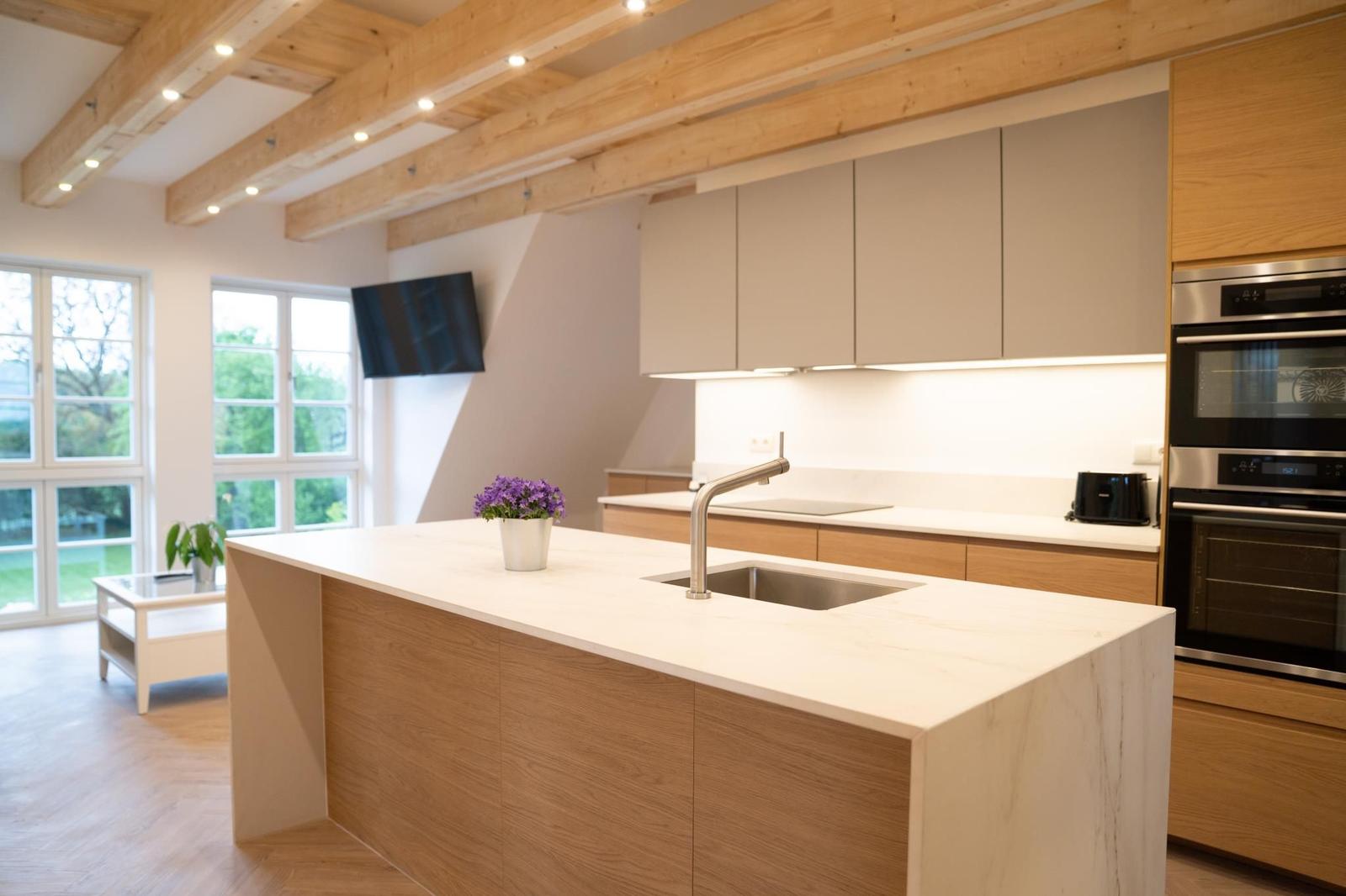 Moderne Küche mit Holzbalken, Edelstahlspüle und integriertem Herd.