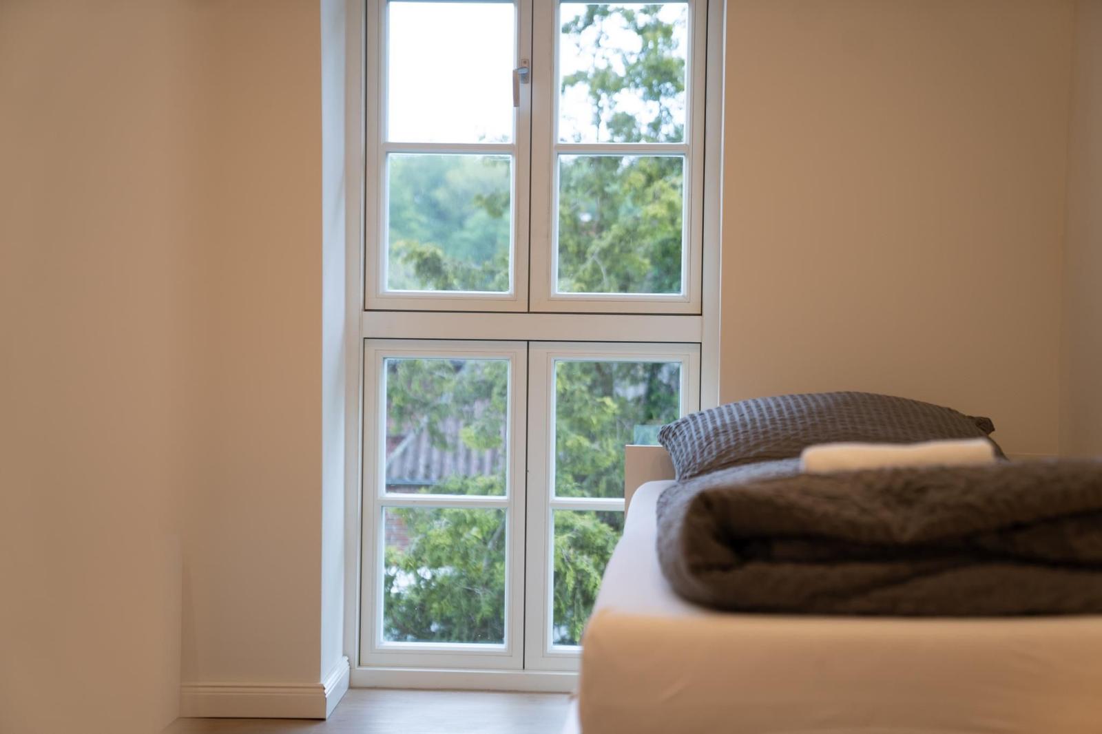 Schlafzimmer mit Bett und Fensterblick auf Bäume