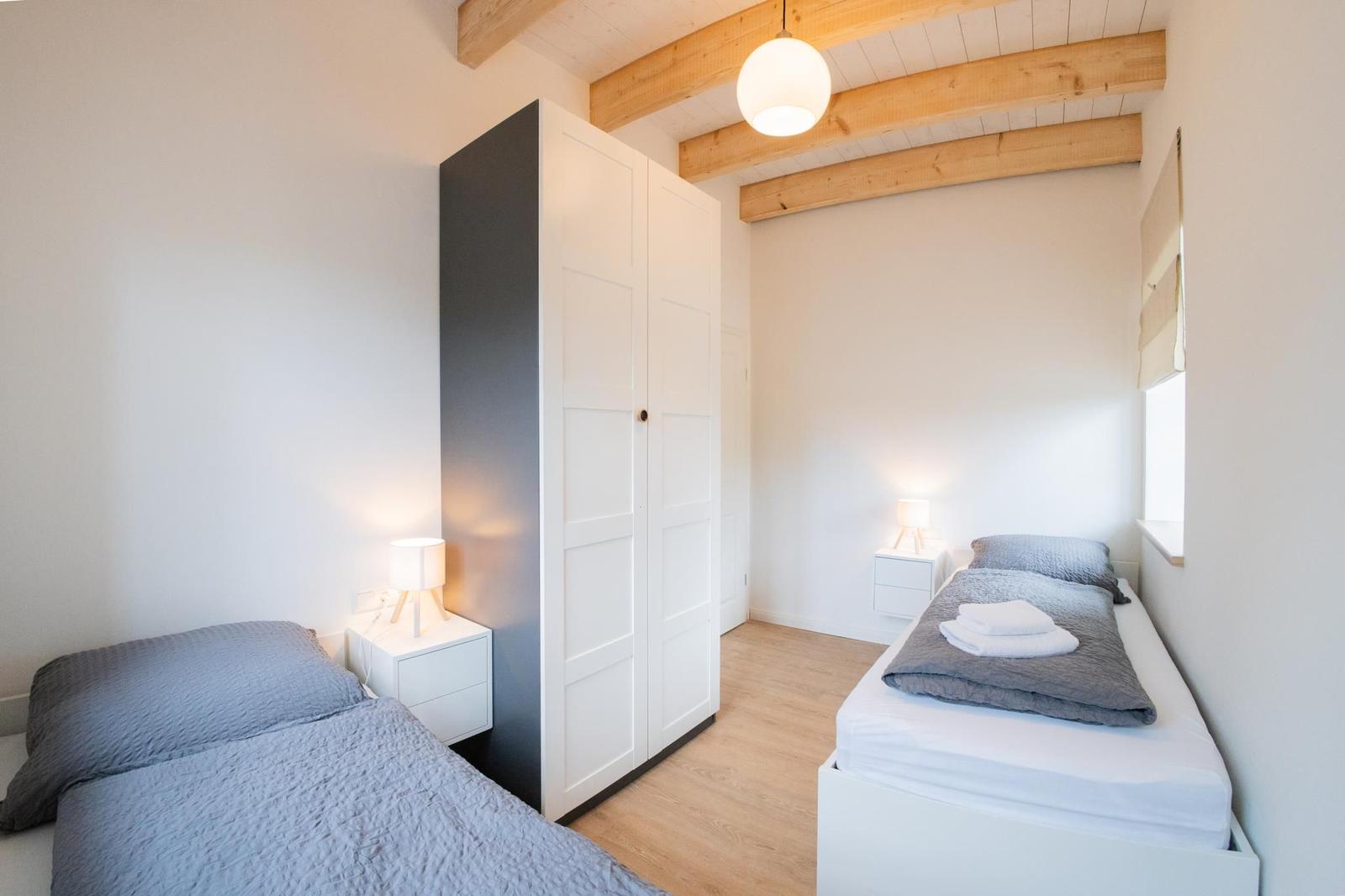 Zwei Betten, Kleiderschrank und Decken. Holzdecke mit Balken.