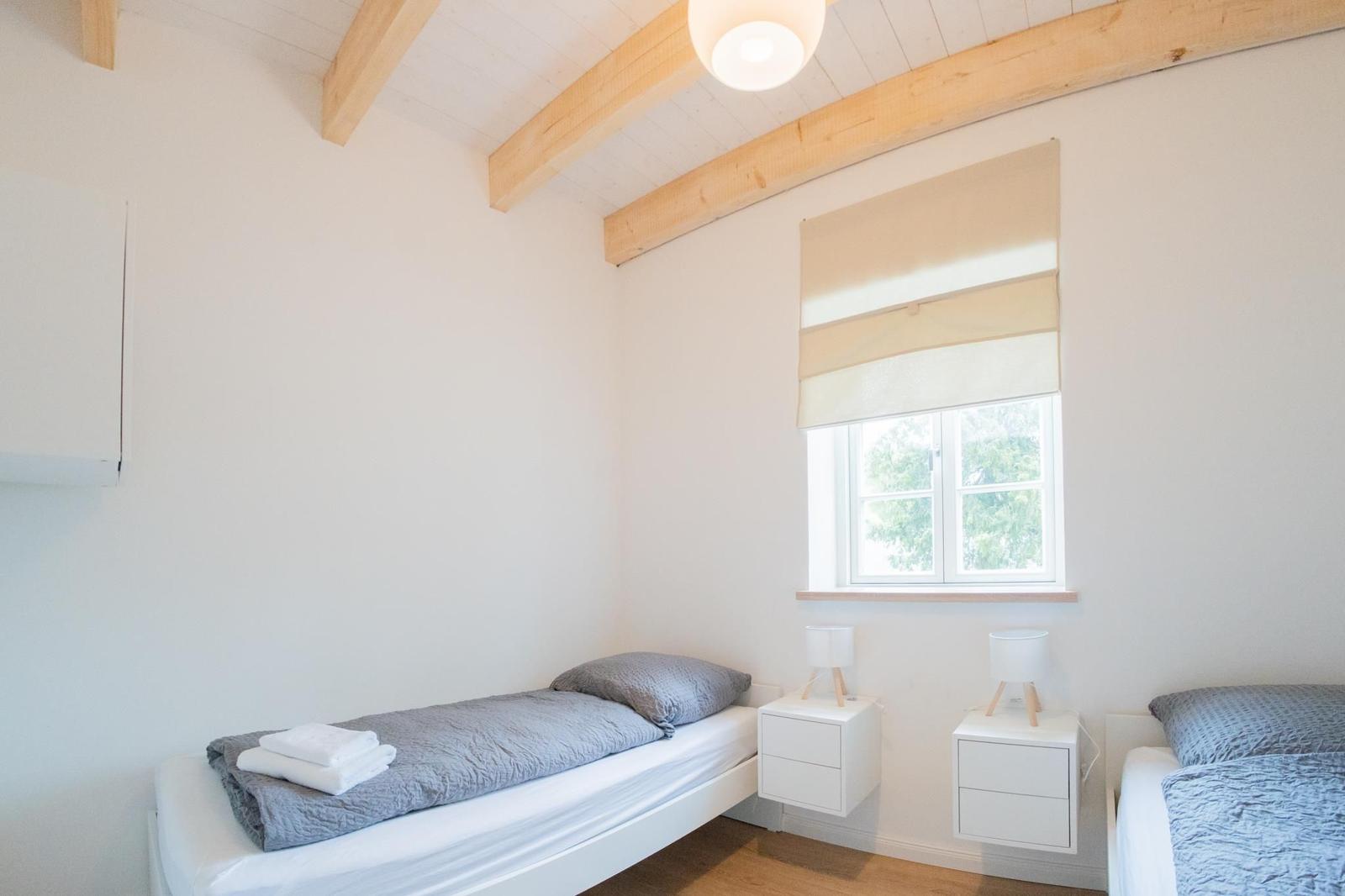 Zimmer mit zwei Betten, Fenster und Holzbalken an der Decke.