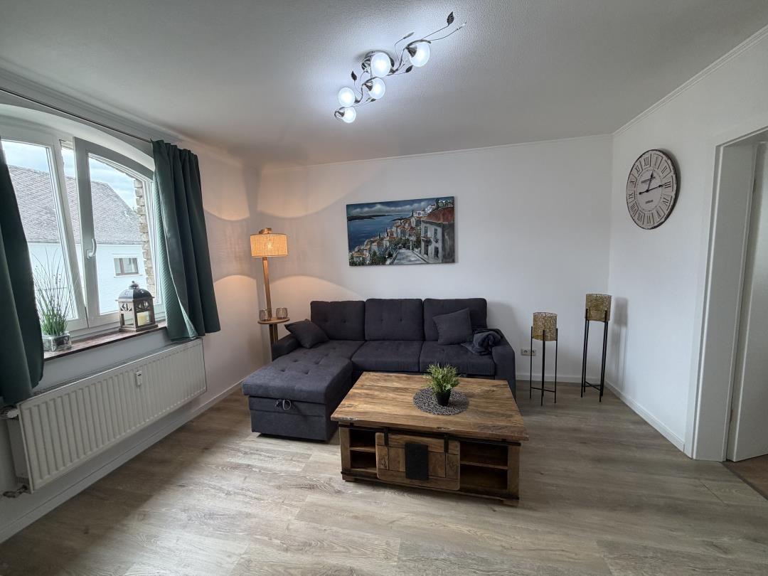 Living room with gray sofa, wooden table, and wall picture.