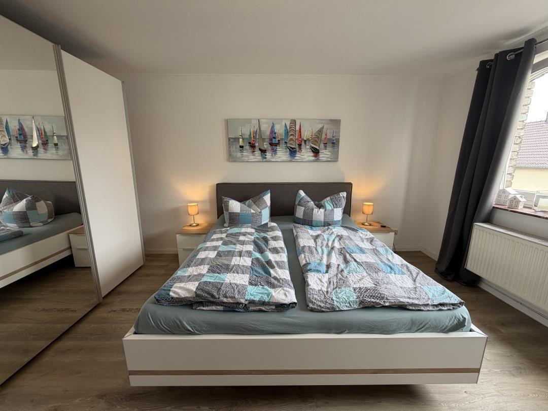 Bedroom with double bed, two nightstands, and wall art with sailboats.