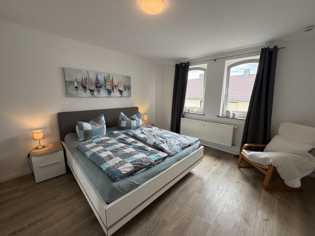Bedroom with double bed, windows, and armchair.