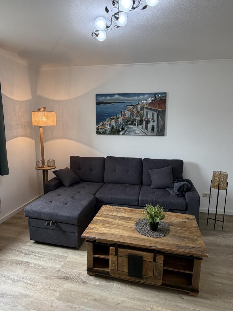 A living room with gray sofa, wooden table, and wall painting.