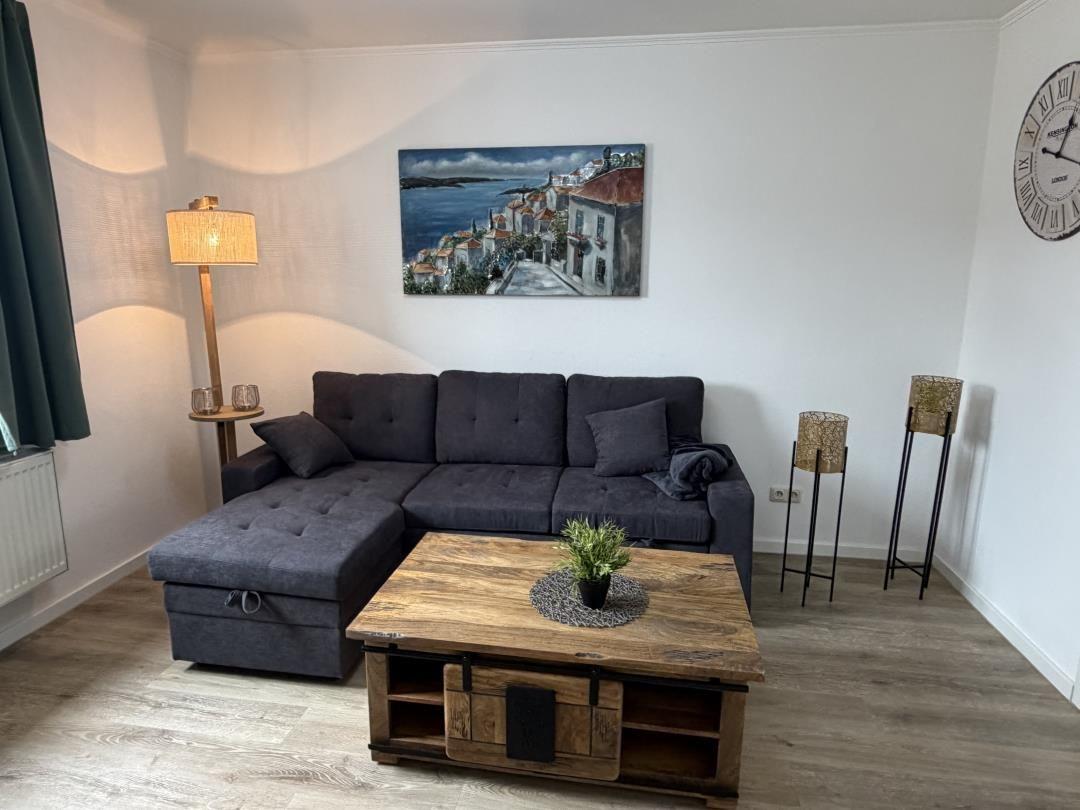 Living room with gray sofa, wooden table, and wall painting.
