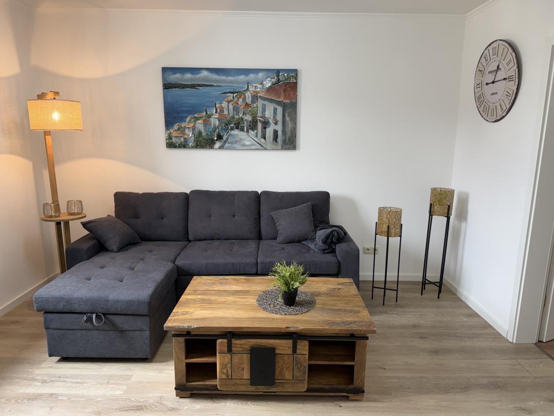 Living room with gray sofa, wooden table, and wall painting.