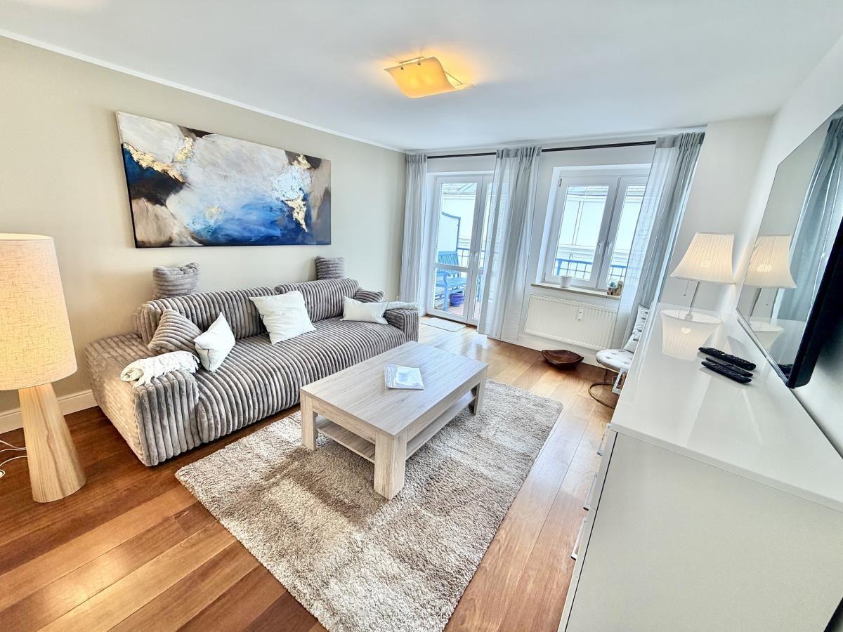 Wohnzimmer mit Sofa, Couchtisch und Blick auf Balkon.