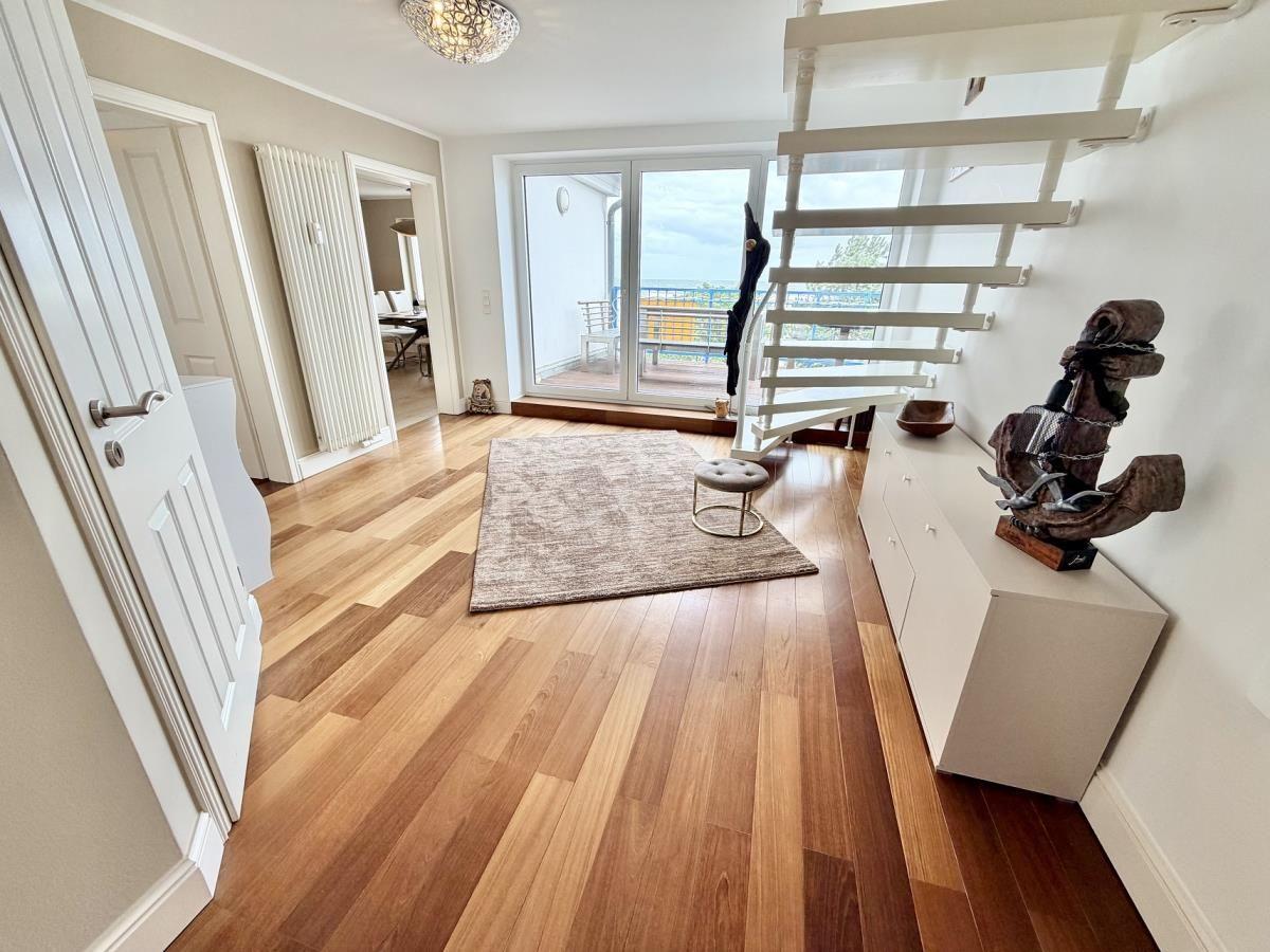 Helle Wohnung mit Holzboden, Balkon und Wendeltreppe. Weiße Möbel und Teppichboden.