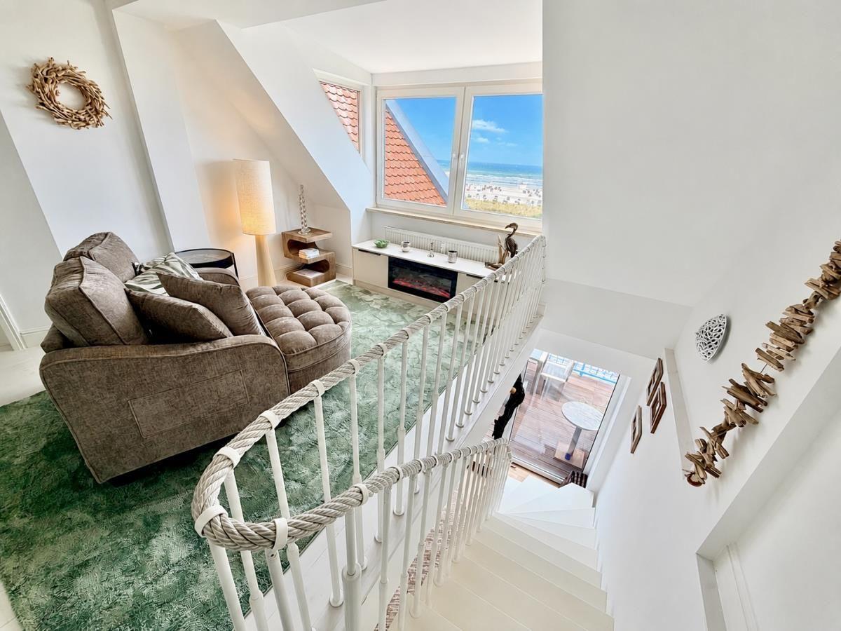 Wohnzimmer mit Sofa, Blick auf Strand und rote Dachziegel