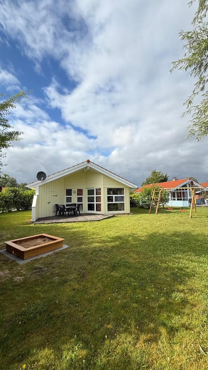 House with garden, terrace, and playground. Wooden frame around sandbox.