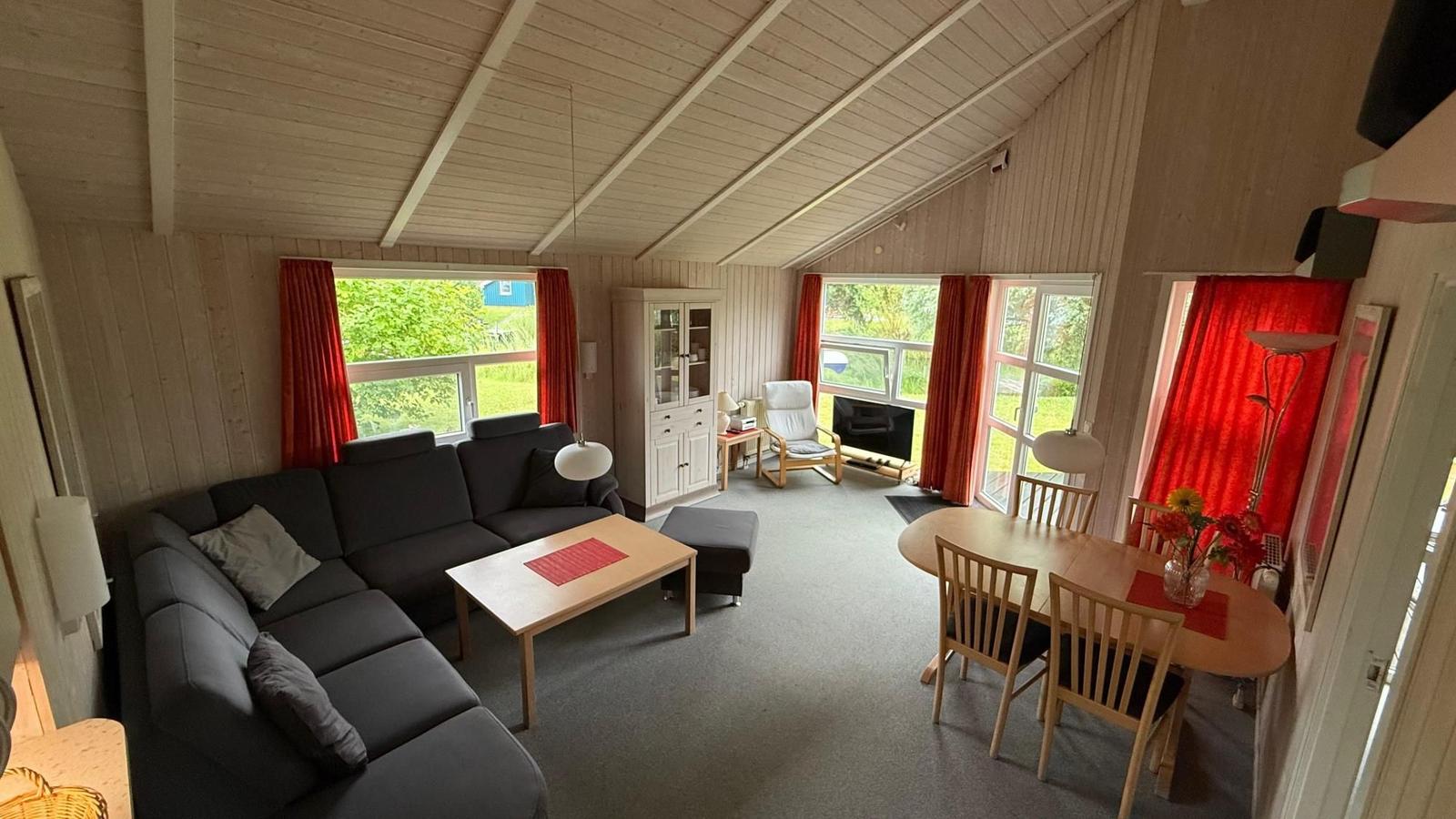 Living and dining area with sofa, dining table, and large windows.