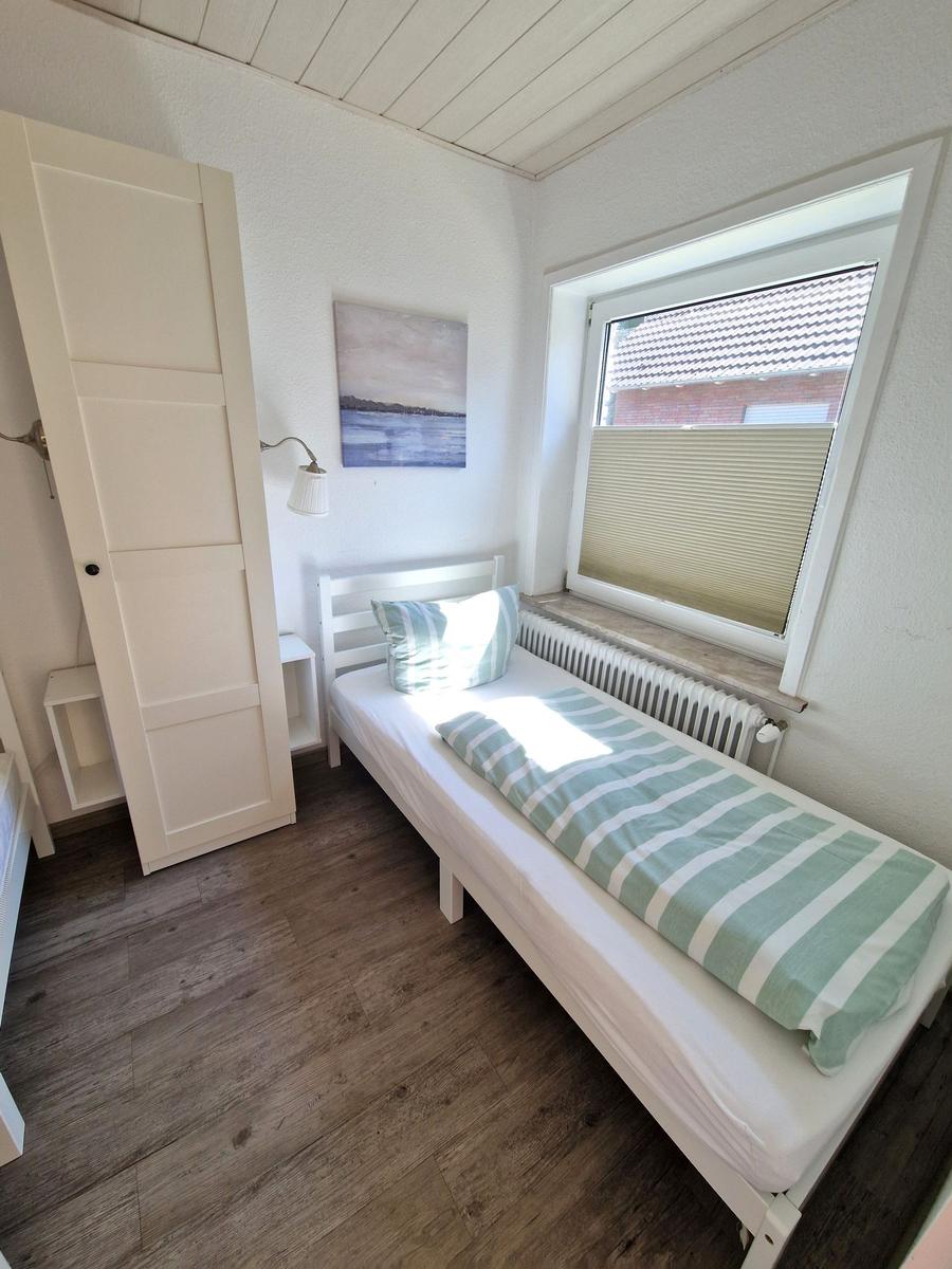 Ein Schlafzimmer mit einem Bett, einem Kleiderschrank und einem Fenster mit Jalousie.