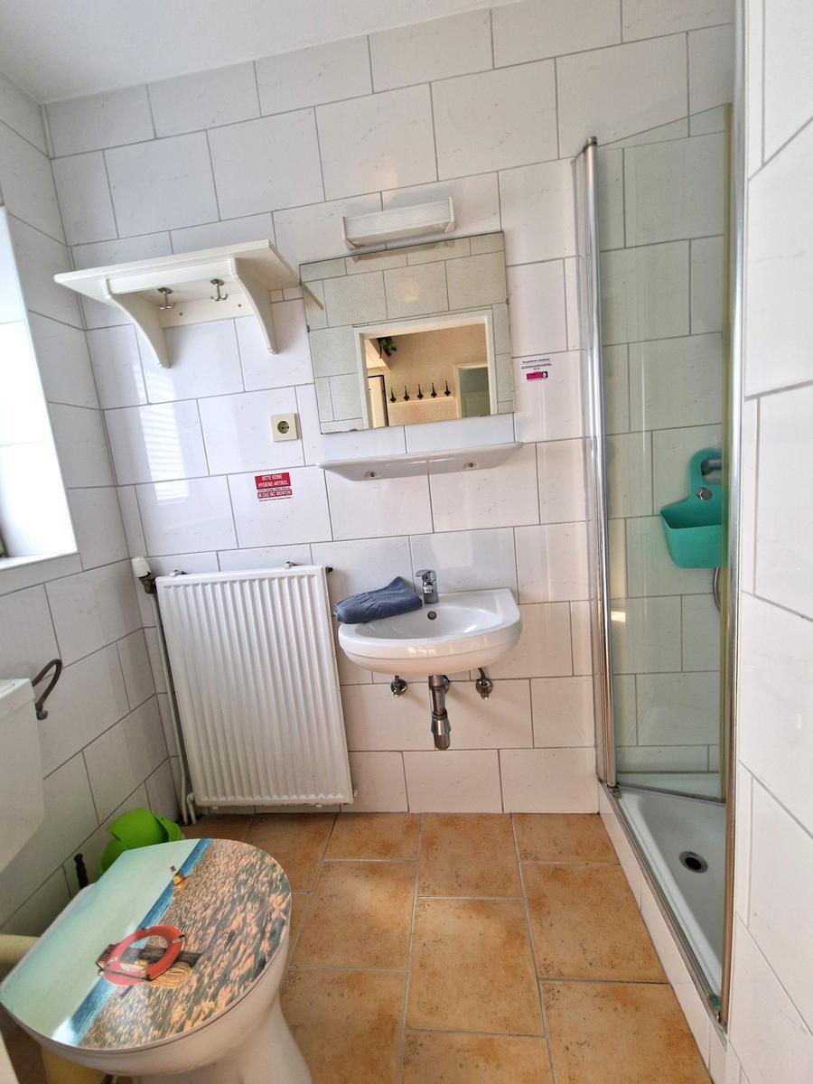 Badezimmer mit Dusche, Waschbecken und Toilette mit Strandmotiv.