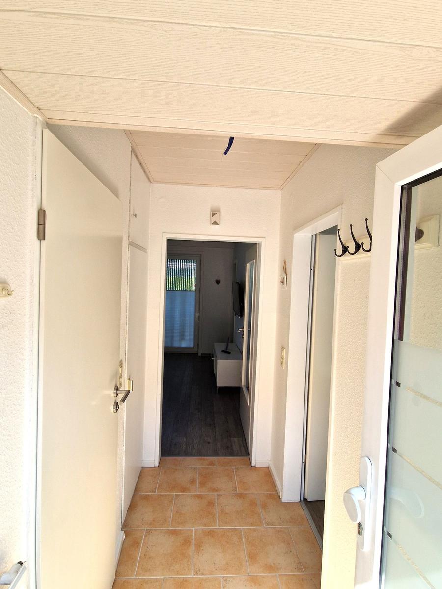 Flur mit Terrassen- und Schlafzimmerzugang, gefliest und mit Haken ausgestattet.