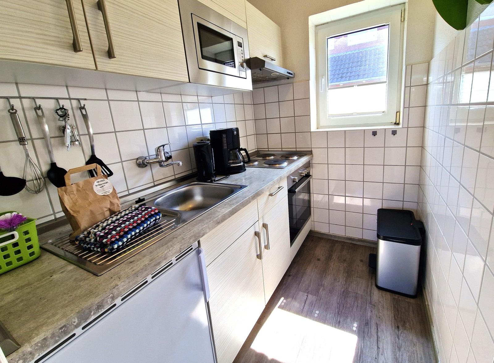 Küche mit Spüle, Herd, Mikrowelle und Fenster
