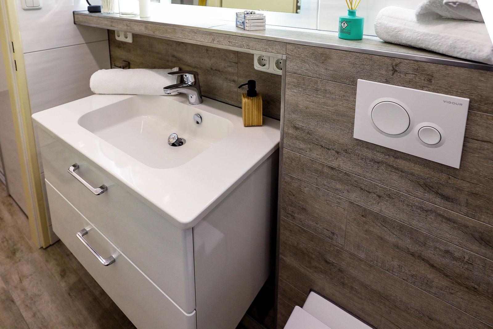 Waschbecken mit Spiegelschrank, Toilettenbedienfeld und Handtuch.