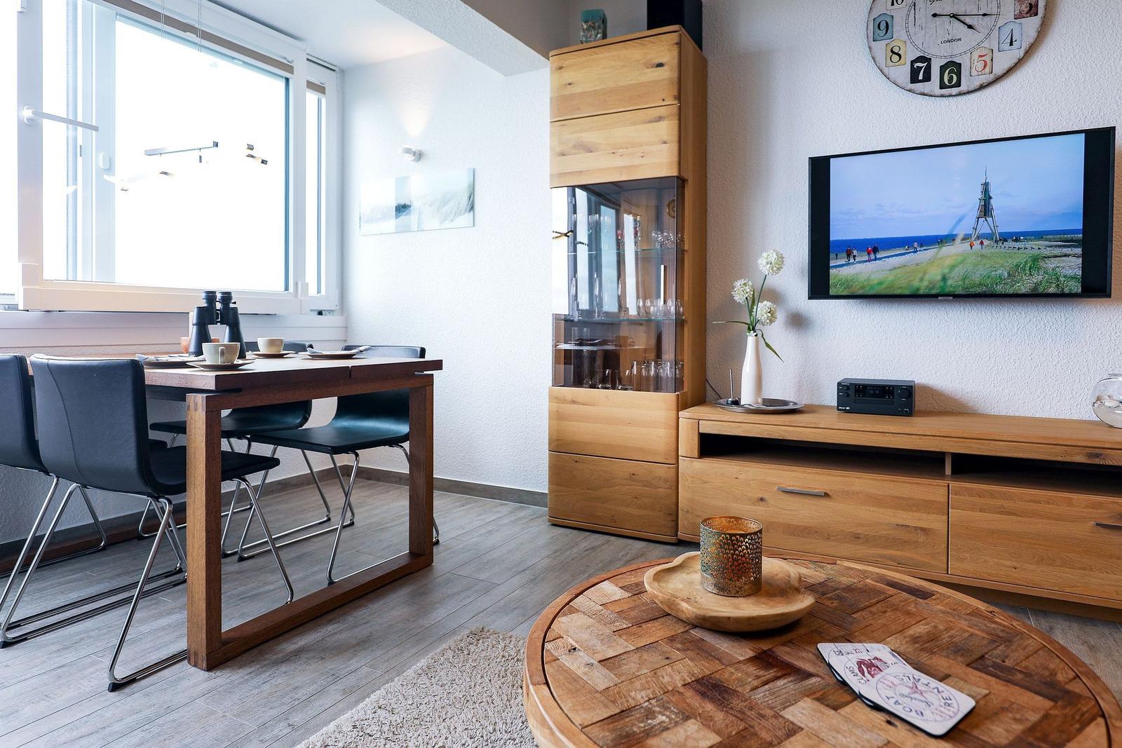 Wohn- und Essbereich mit Holzmöbeln, Fernseher und Tisch mit Stühlen.