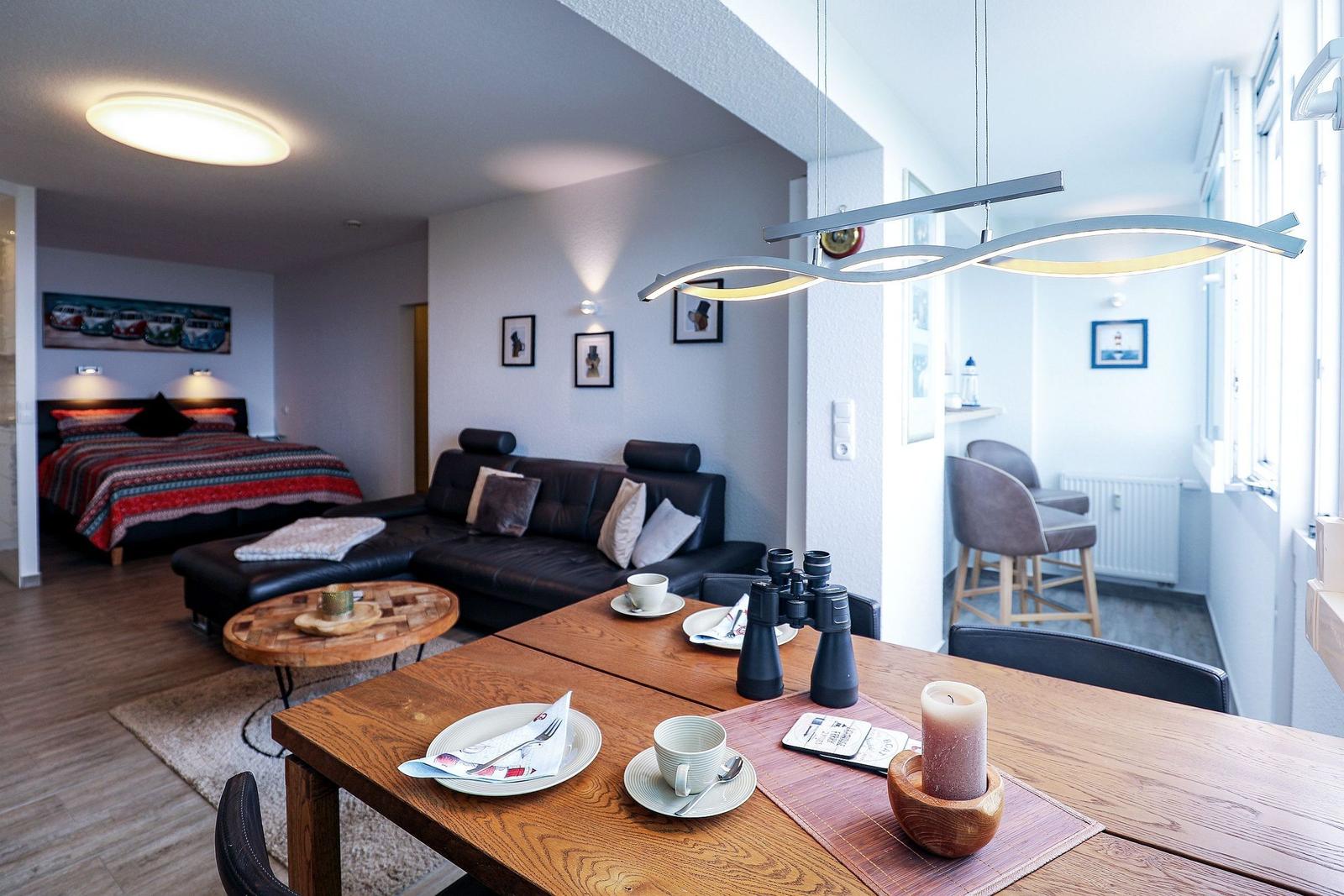 Wohnung mit Essbereich, Sofa und Schlafzimmer im Hintergrund.