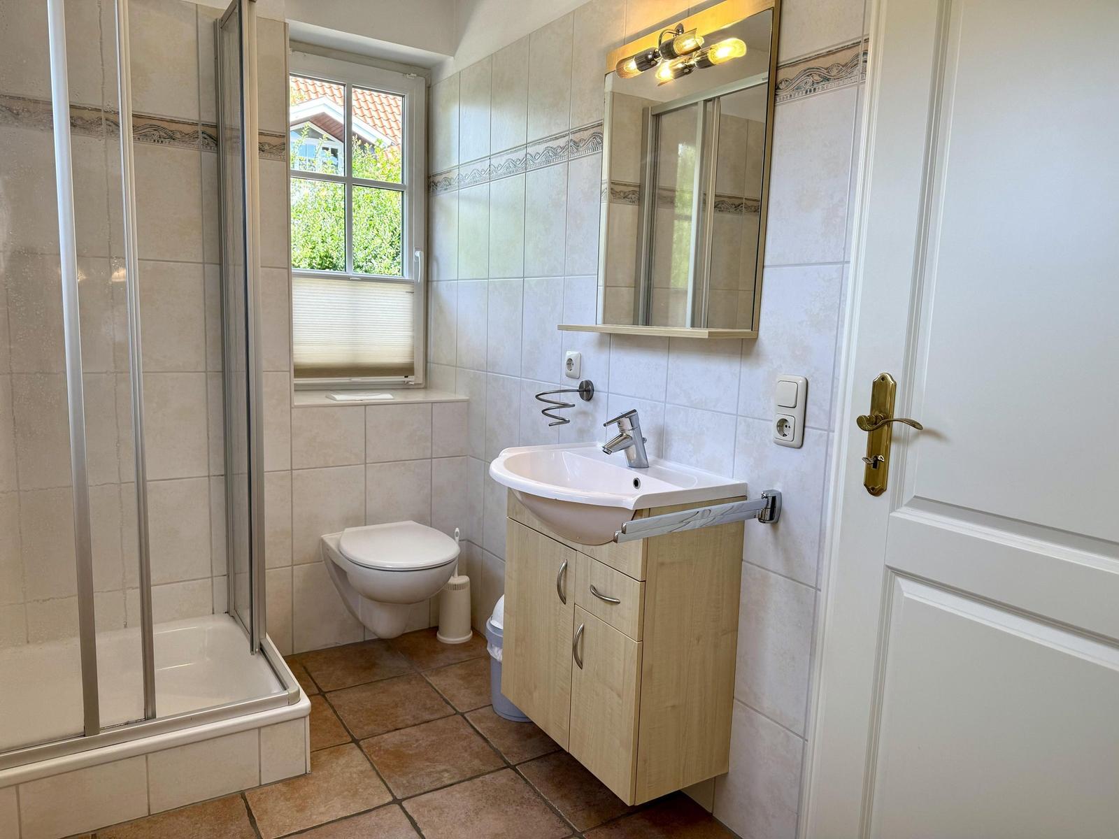 Badezimmer mit Dusche, Toilette und Waschbecken mit Spiegel