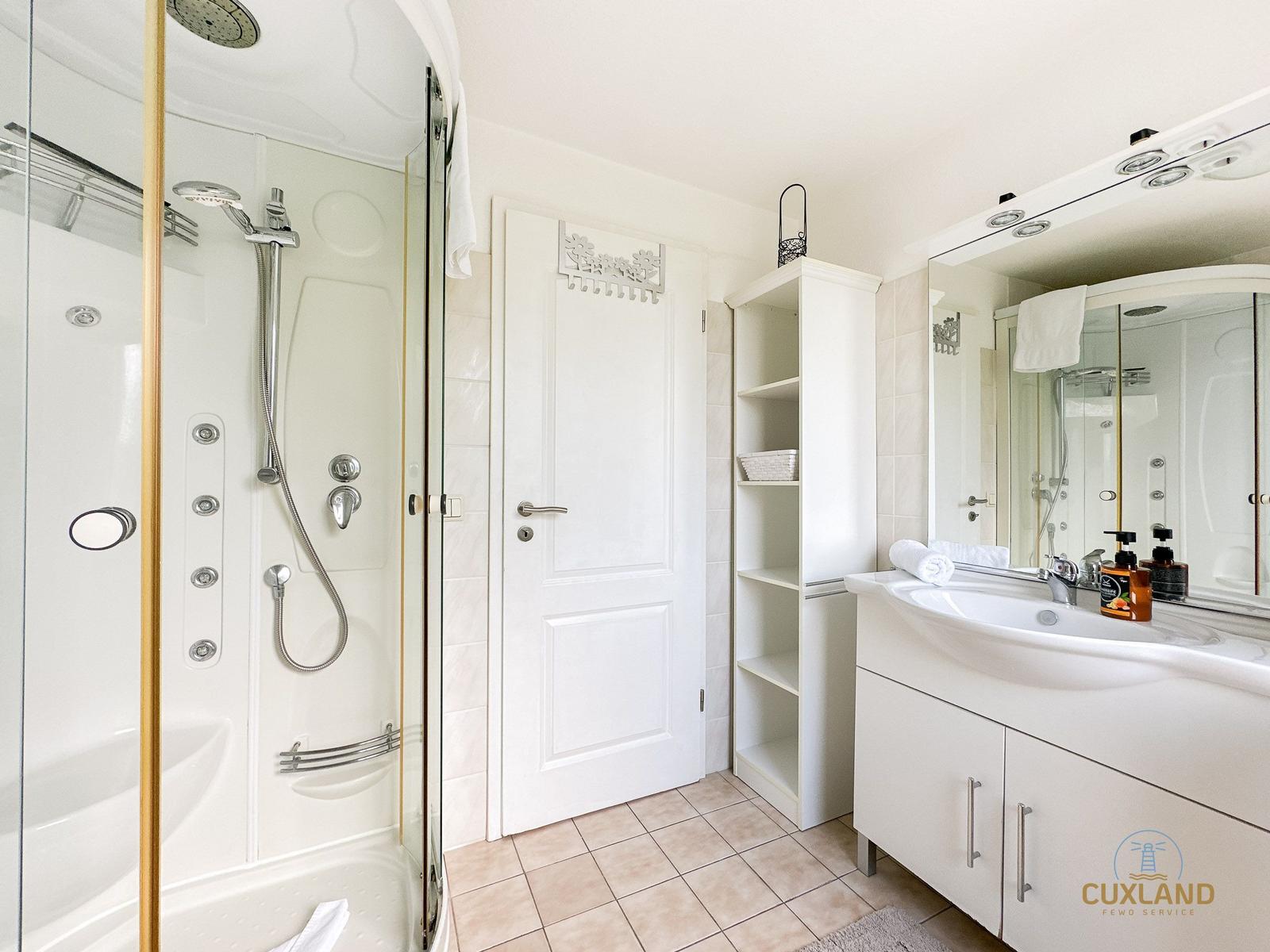 Badezimmer mit Dusche, Waschbecken und Regal