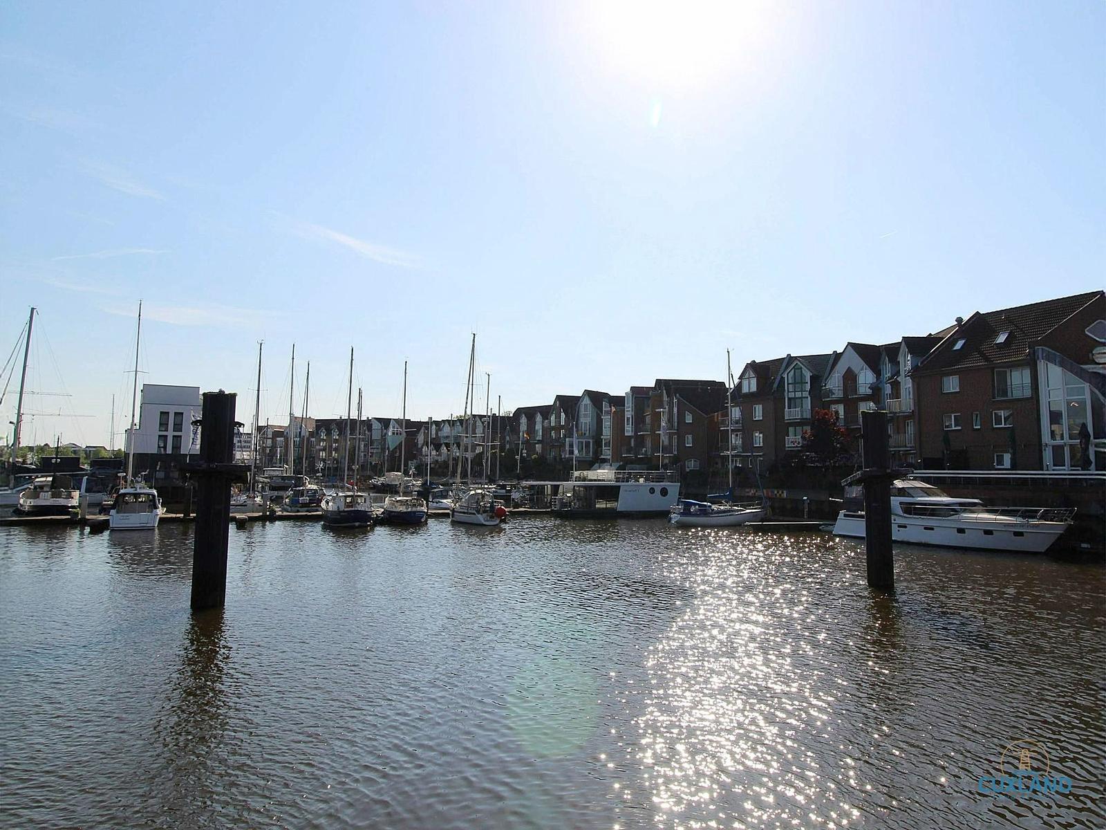 Hafen mit Booten und Häusern unter blauem Himmel.