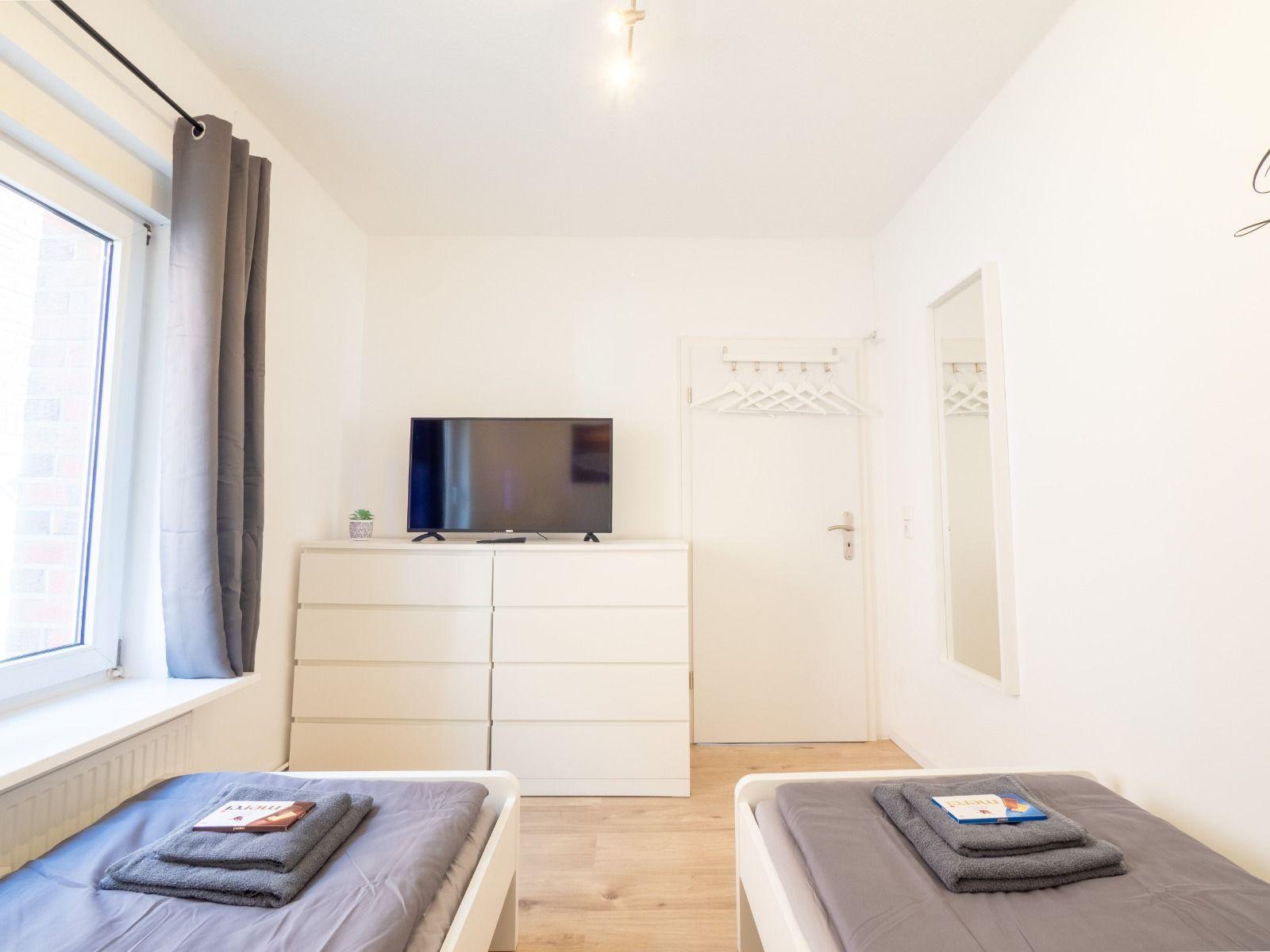 Zwei Betten, Fernseher und Kleiderschrank im Schlafzimmer.