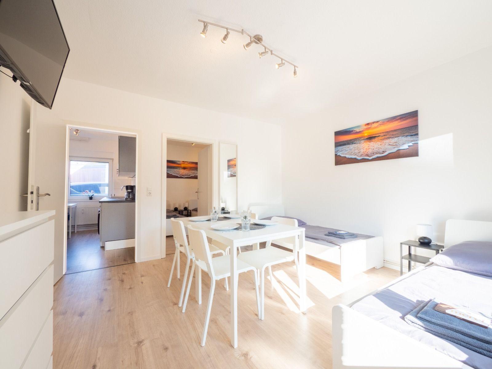 Wohnung mit Schlafzimmer, Essbereich und Küche. Wandbild zeigt Sonnenuntergang.