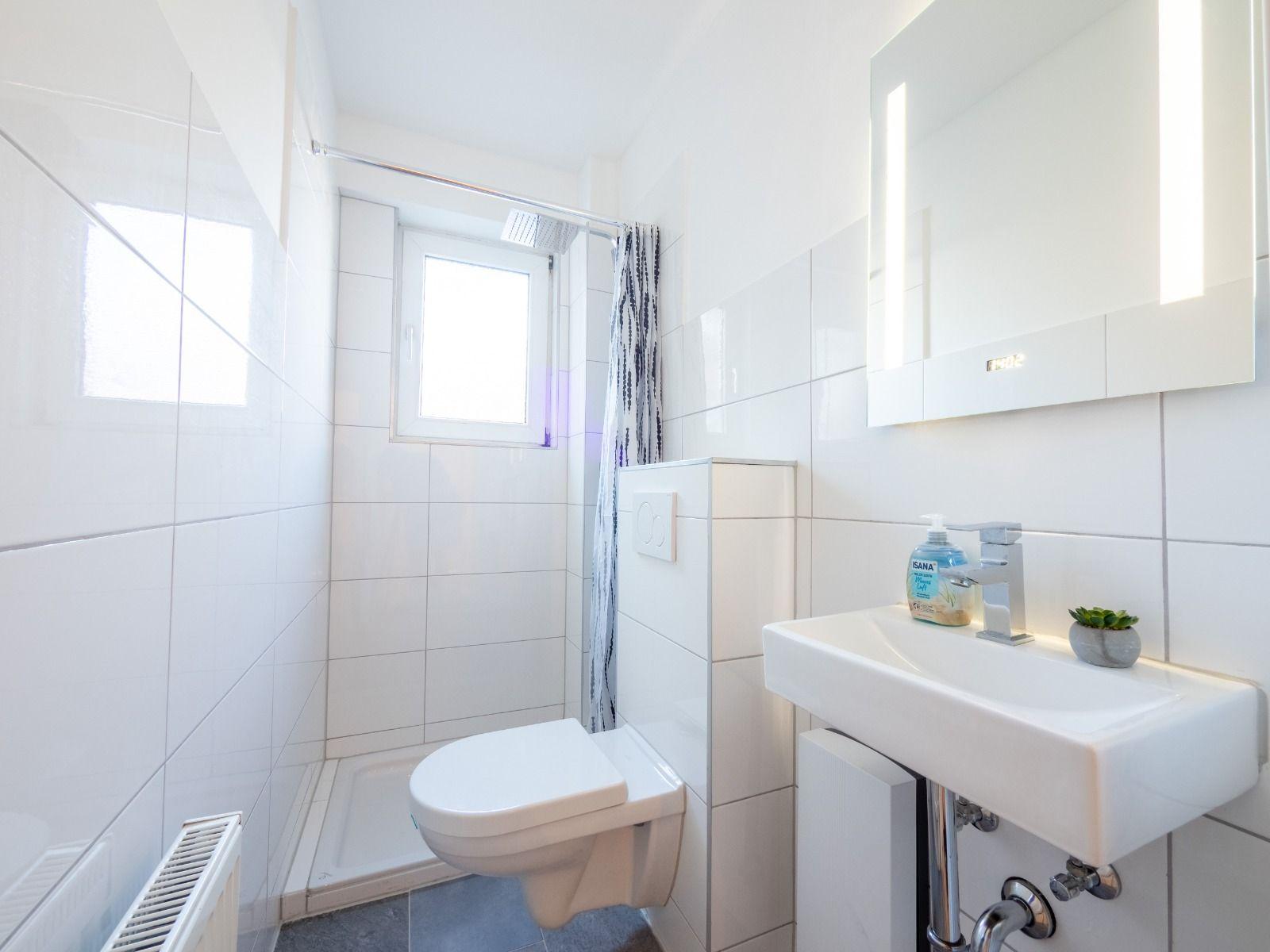 Badezimmer mit Dusche, Toilette und Waschbecken mit Spiegel