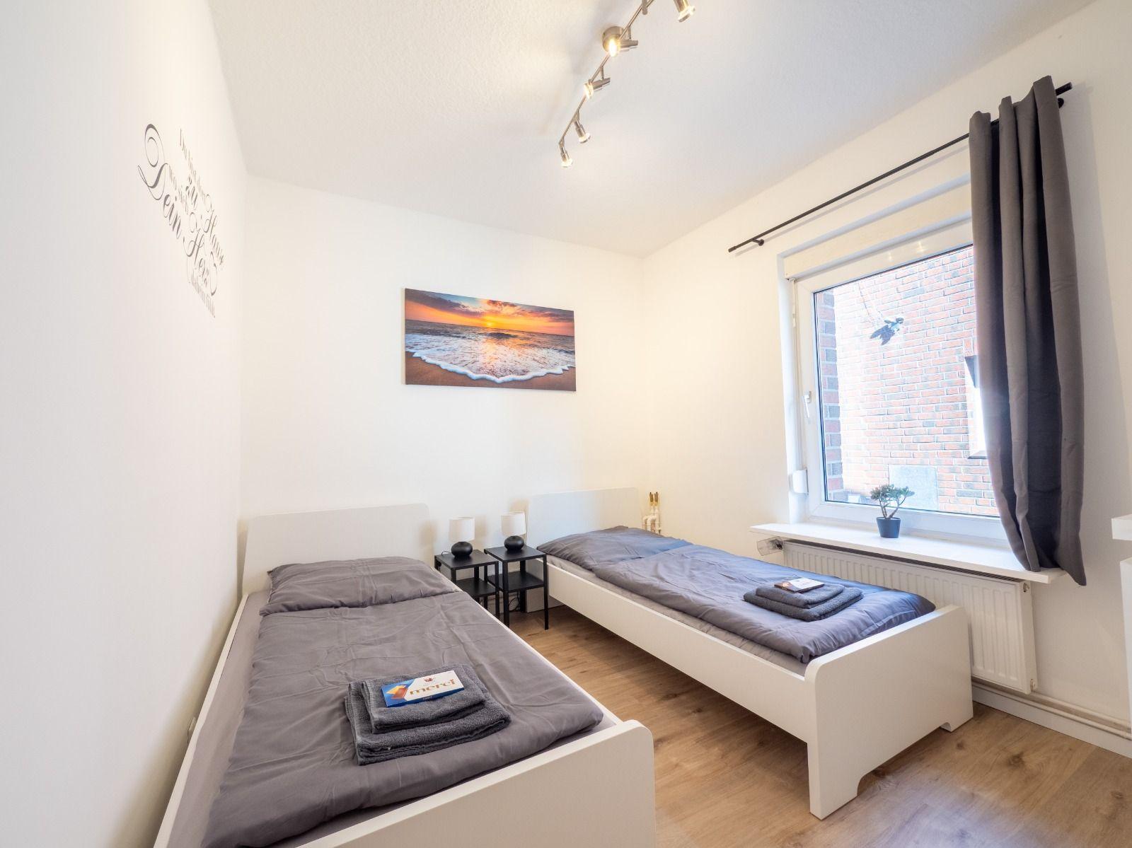 Zwei Einzelbetten, Wandbild und Fenster mit Vorhang.