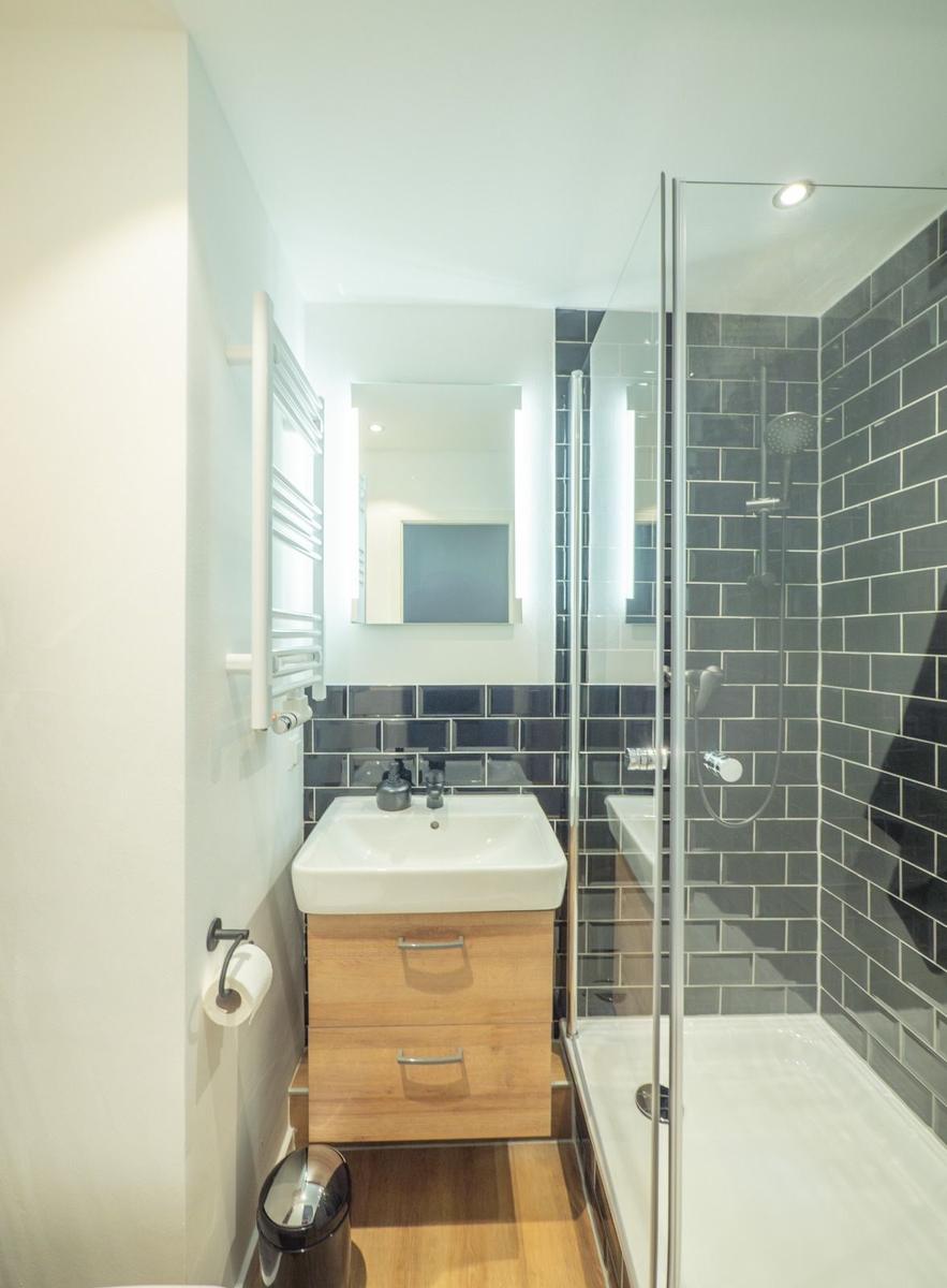 Badezimmer mit Dusche, Waschbecken und Heizkörper