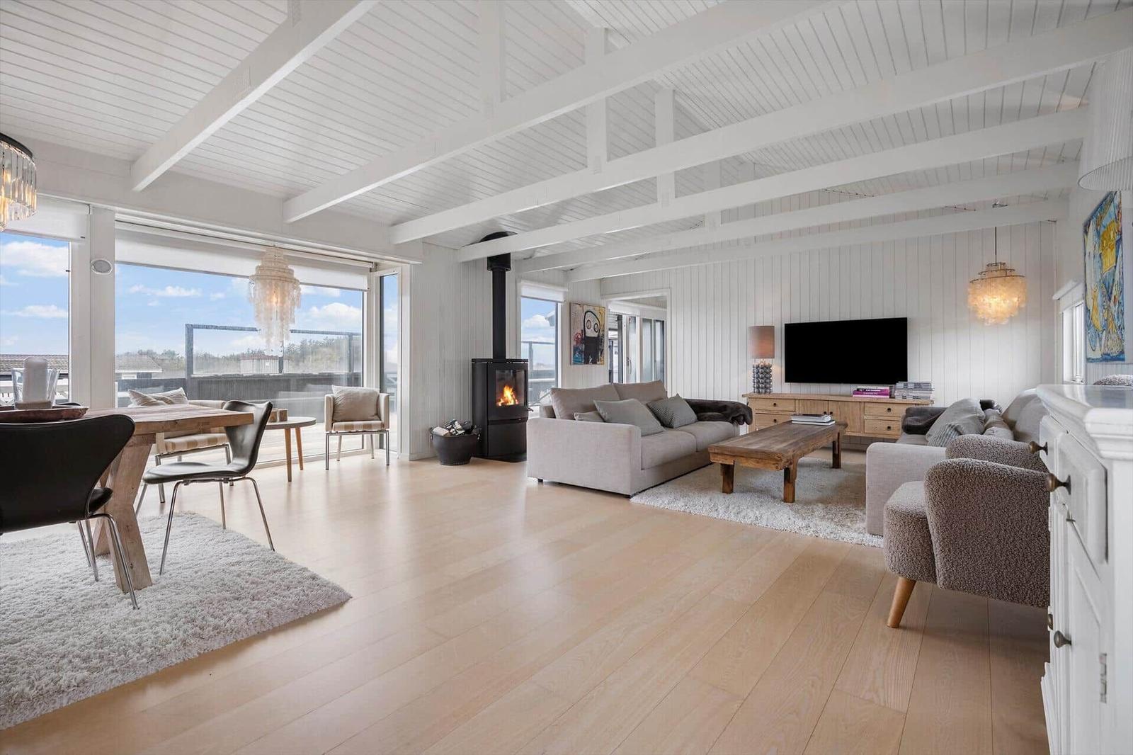 Großes Wohn- und Esszimmer mit Holzboden, Kamin und großen Fenstern.