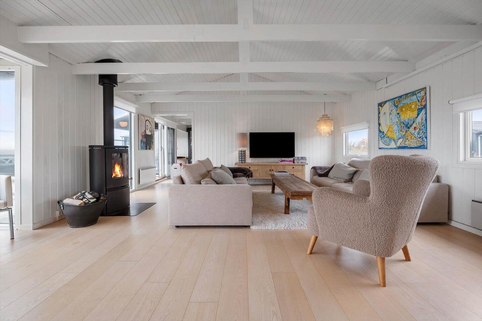 Wohnzimmer mit Kamin, Sofa und Fernseher. Holzboden und weiße Wände.