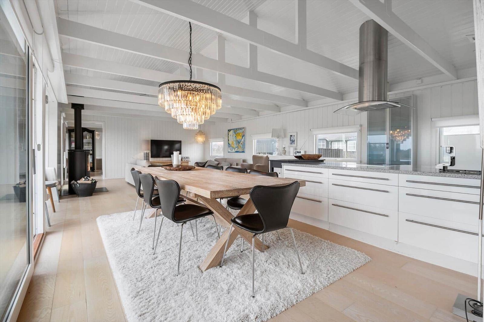 Eingangsbereich mit Essbereich, Küche und Wohnzimmer. Holzfußboden, weißer Teppich und Esstisch mit Stühlen.