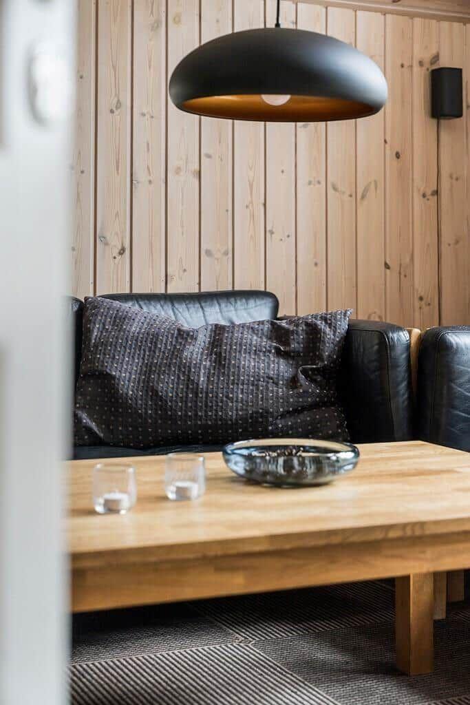 Ein Wohnzimmer mit einem schwarzen Sofa, einem Holztisch und einer Deckenleuchte.