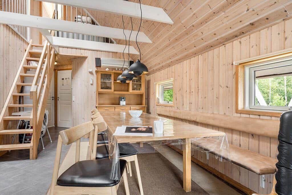 Essbereich mit Holztisch, Bänken und Treppe zur oberen Etage.
