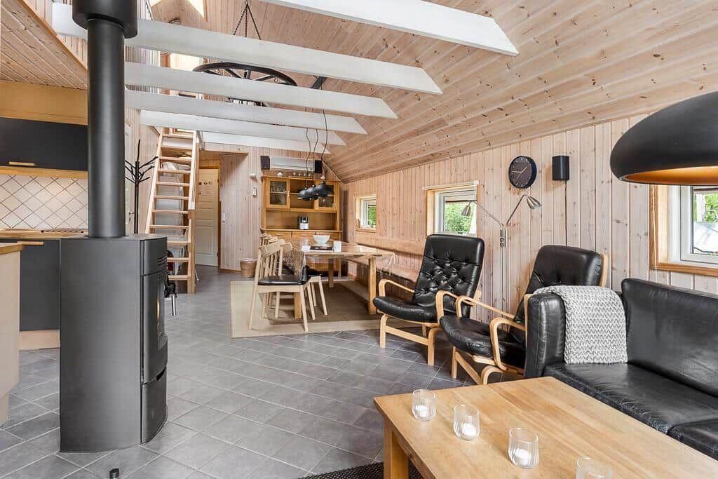 Wohnbereich mit Holzdecke, Kamin und Ledermöbeln.