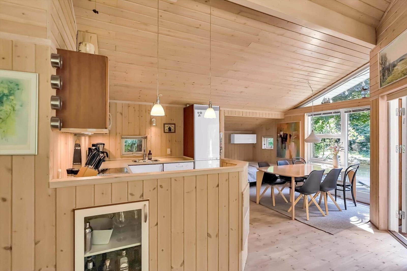 Küche mit Essbereich, Holzwände und -decke, Fenster mit Blick auf Garten.