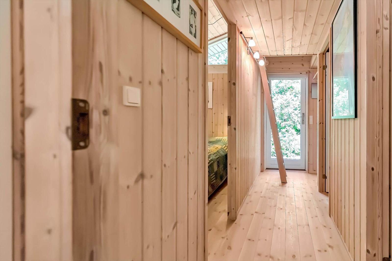 Flur mit Holzwänden und Tür zum Garten. Im Hintergrund ist ein Schlafzimmer sichtbar.