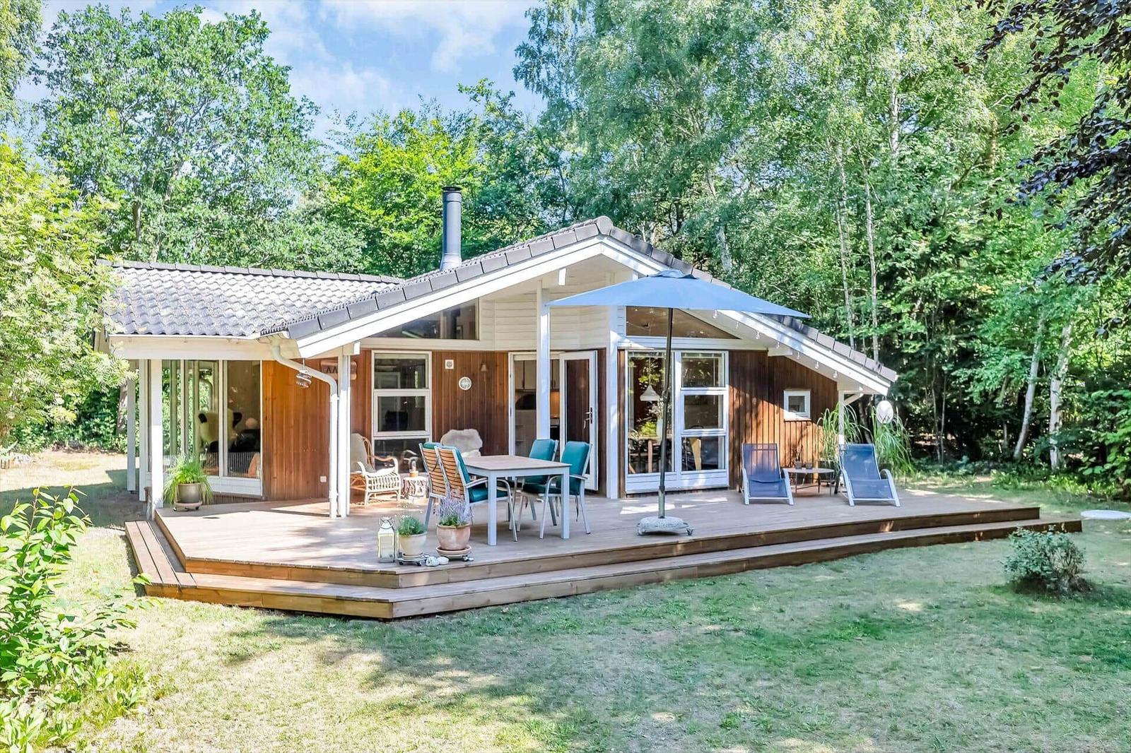 Haus mit Holzterrasse, Garten und Blick in den Wald.