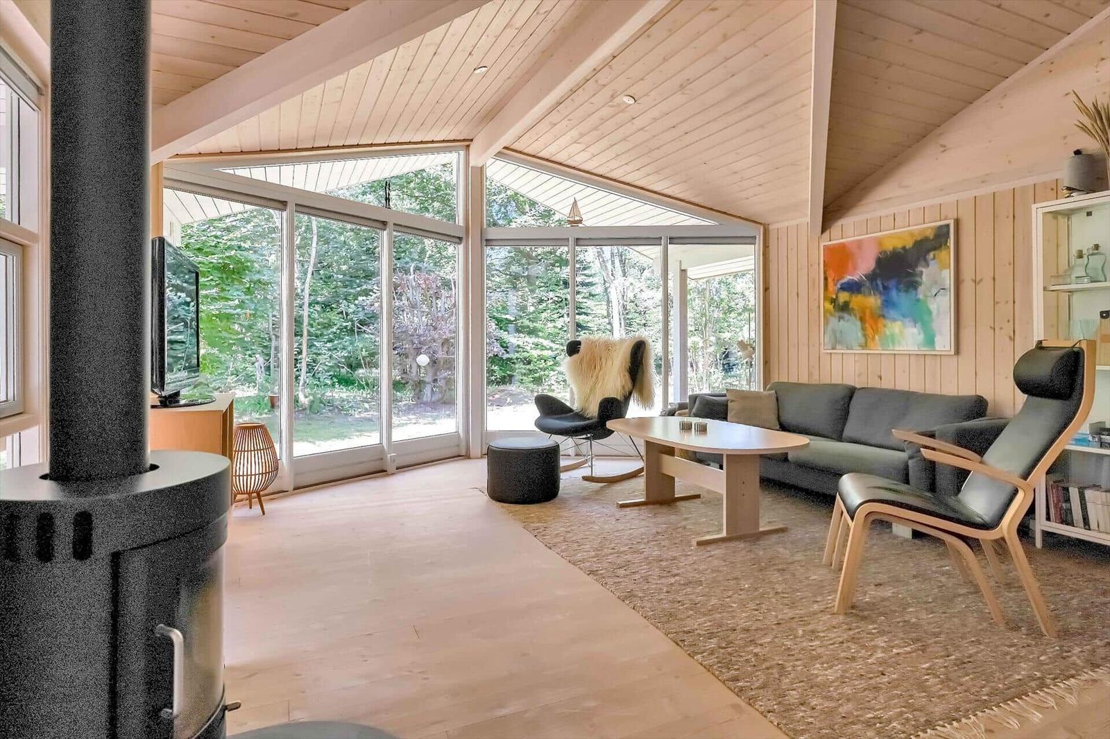 Wohnzimmer mit Holzdecke, Glasfront und Sitzgelegenheiten