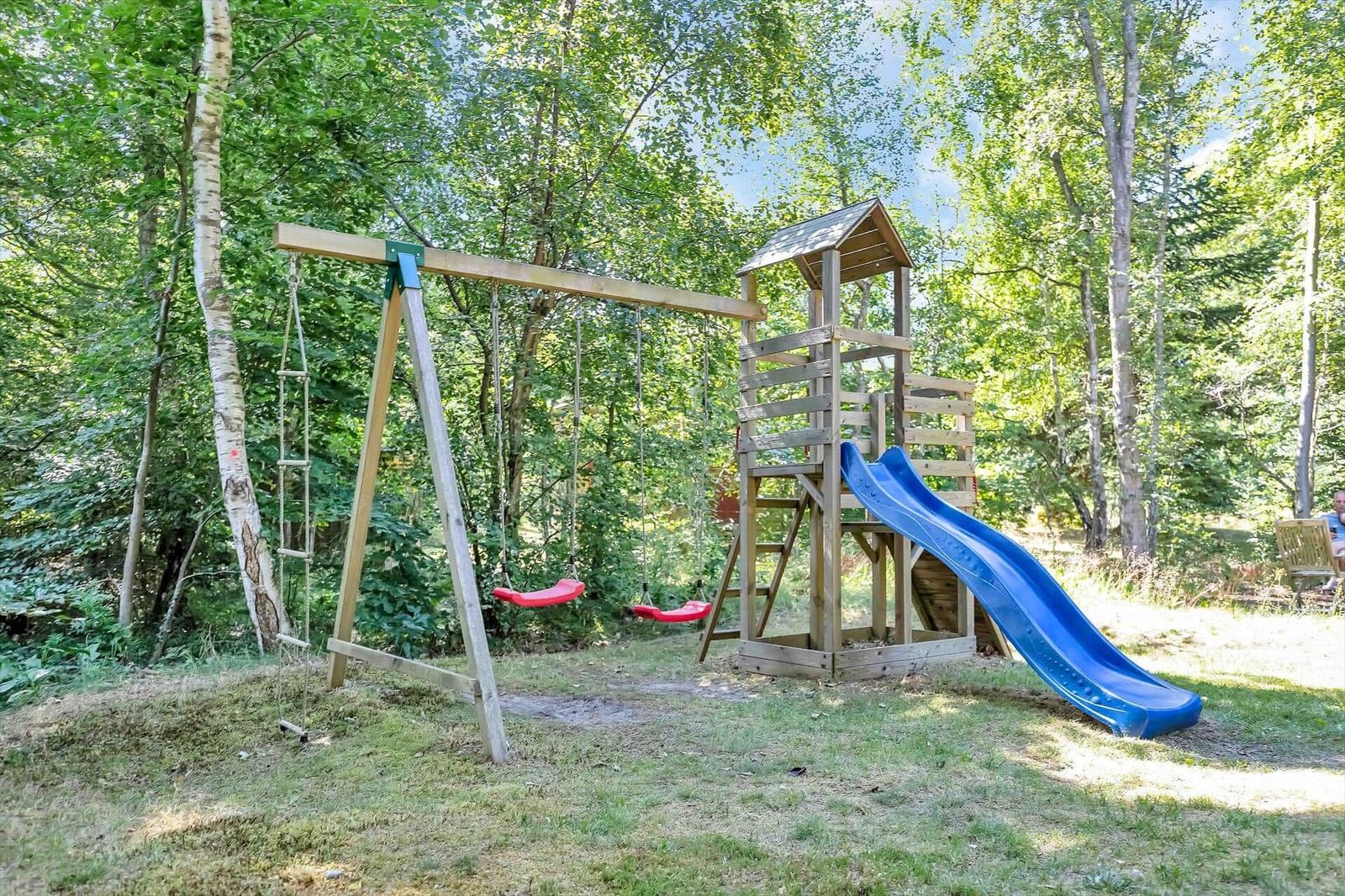 Hinterhof mit Holzspielplatz, Rutsche und Schaukel im Wald.