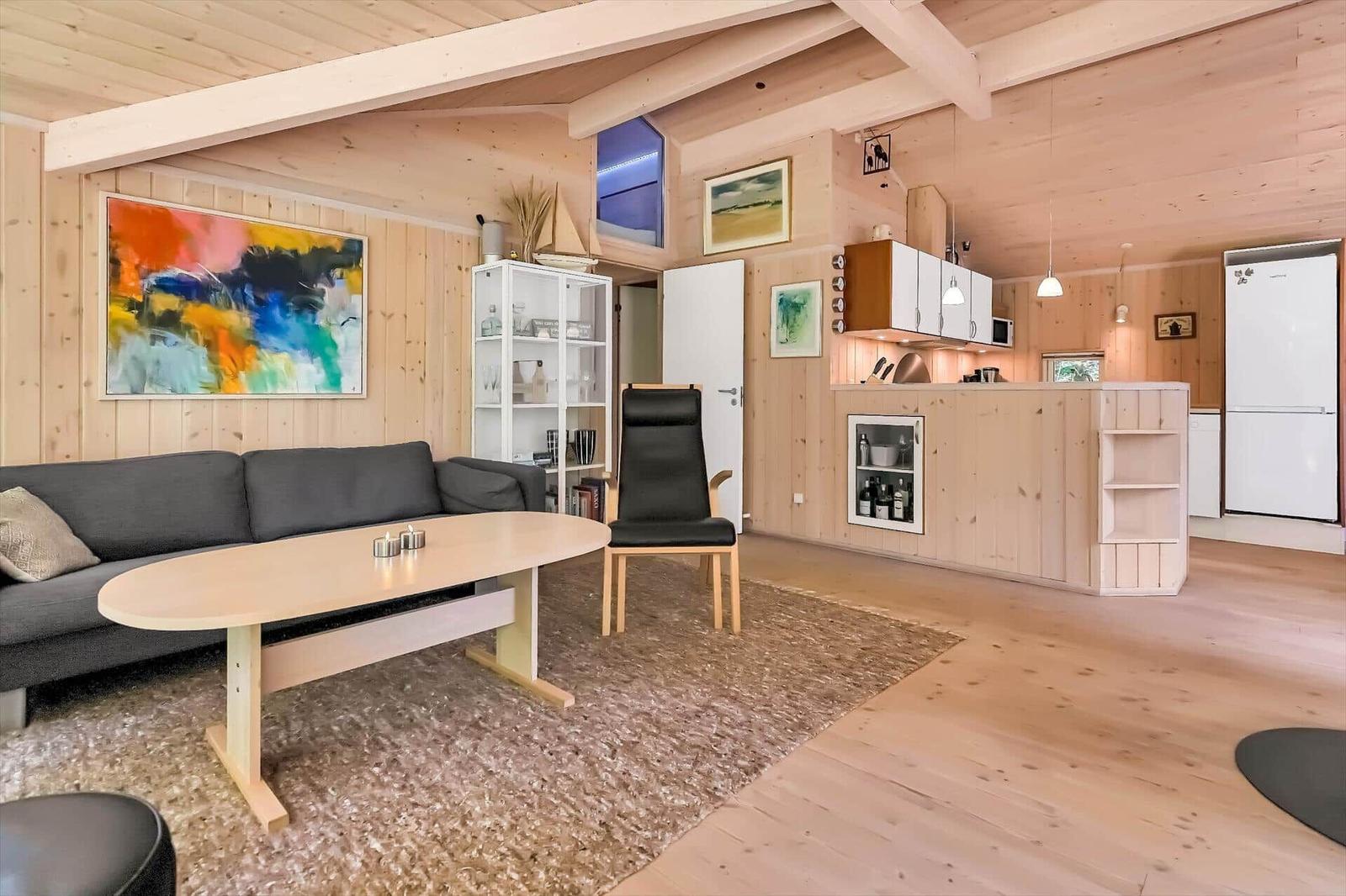 Wohn- und Küchenbereich mit Holzwandverkleidung und moderner Einrichtung.