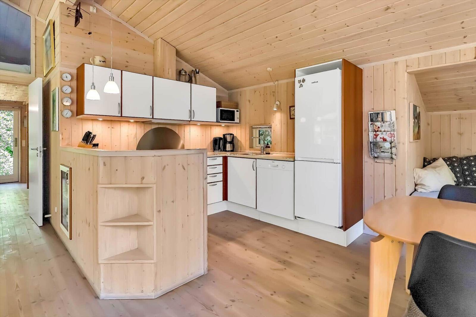 Küche mit Holzdecke, weißer Kühlschrank und Essbereich