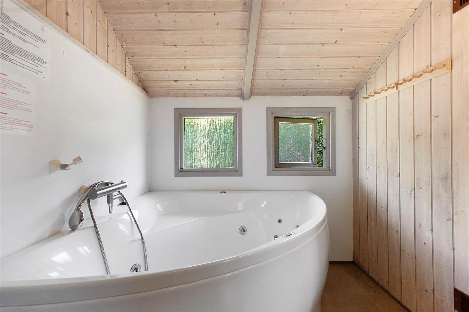 Bad mit Whirlpool, Holzwand und zwei Fenstern